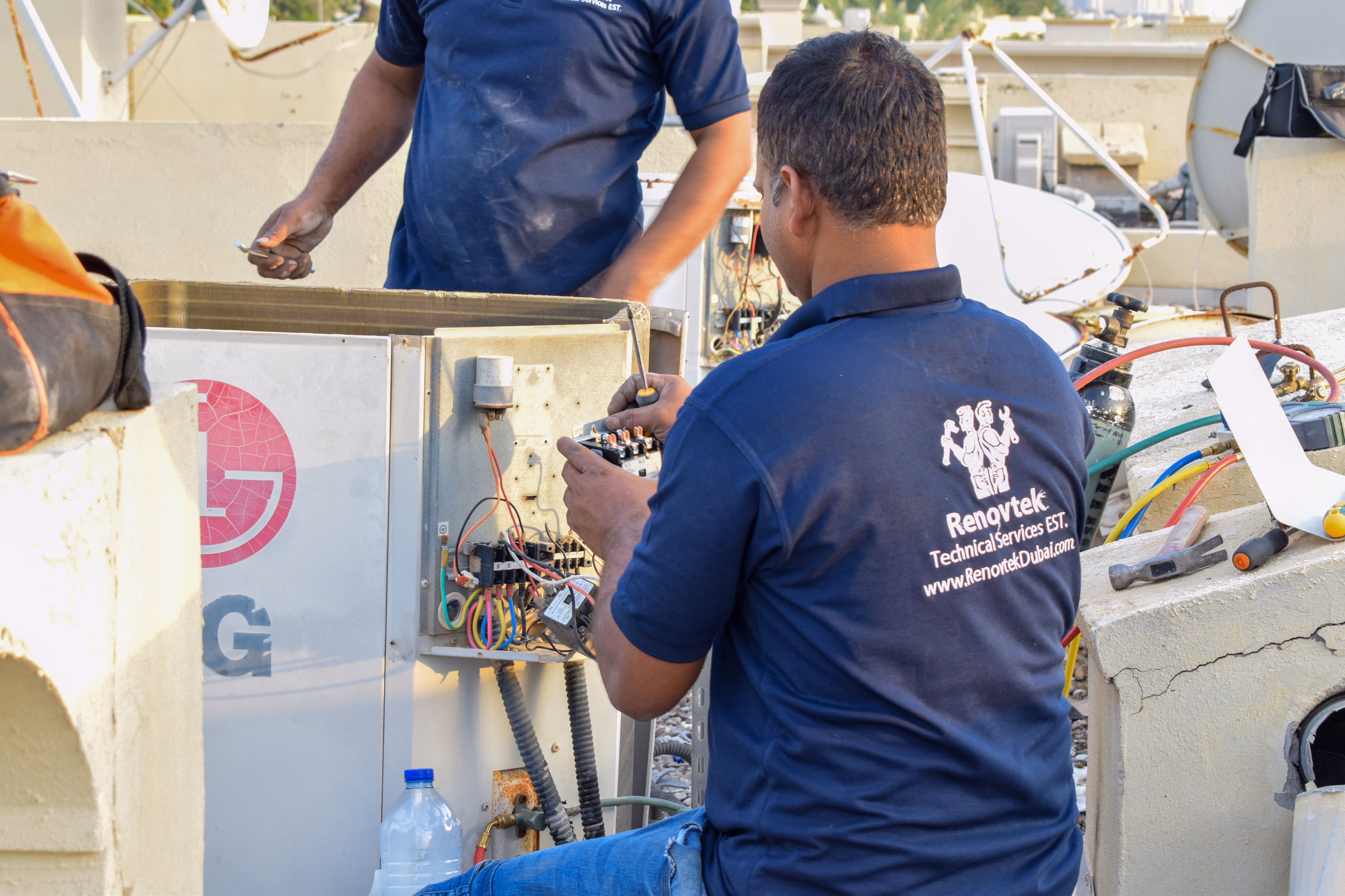 AC technician at work doing electrical repairs at an outdoor AC