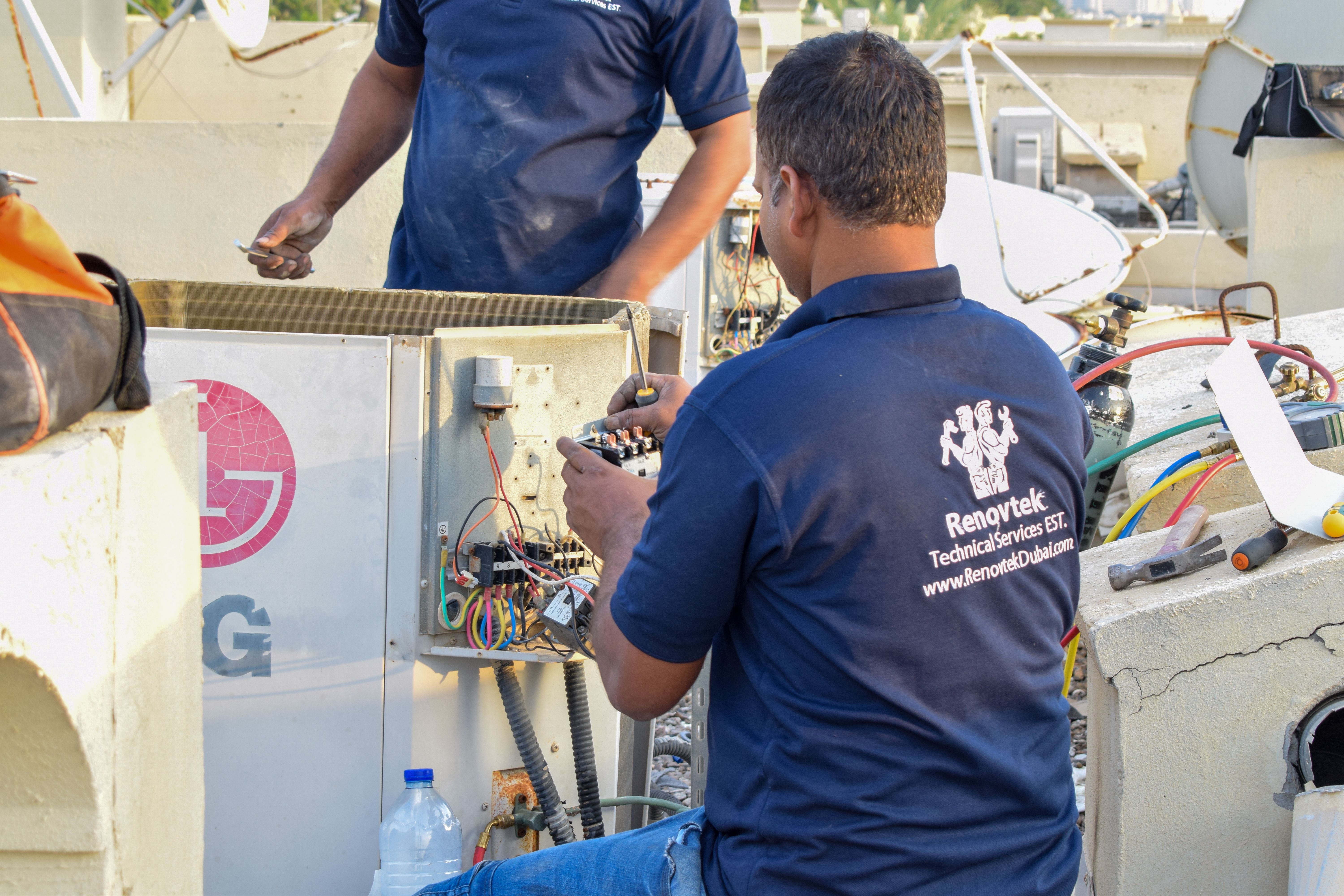 AC technician at work doing electrical repairs at an outdoor AC