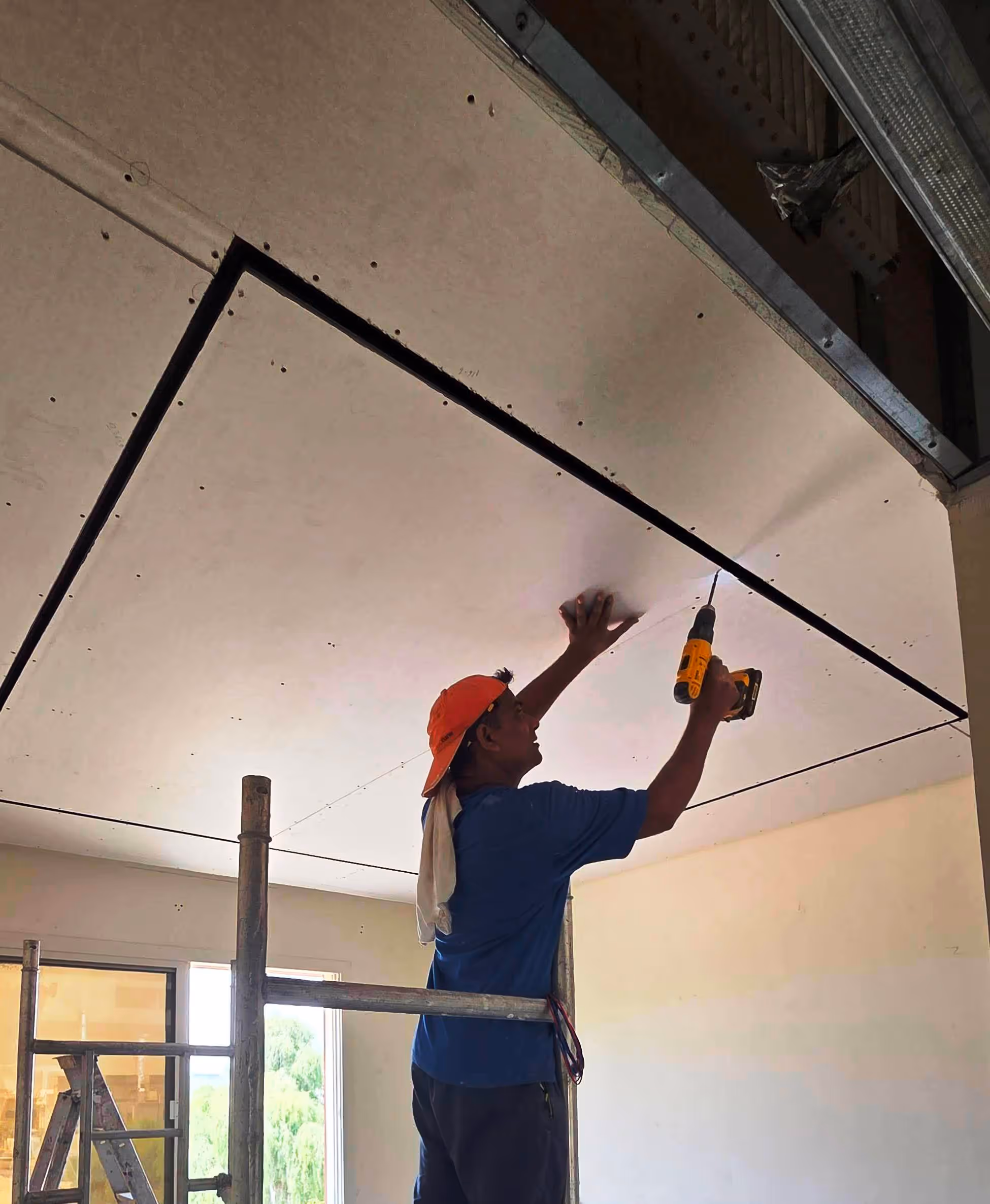 a technisian fixing gypsum board and creating a decorative false ceiling
