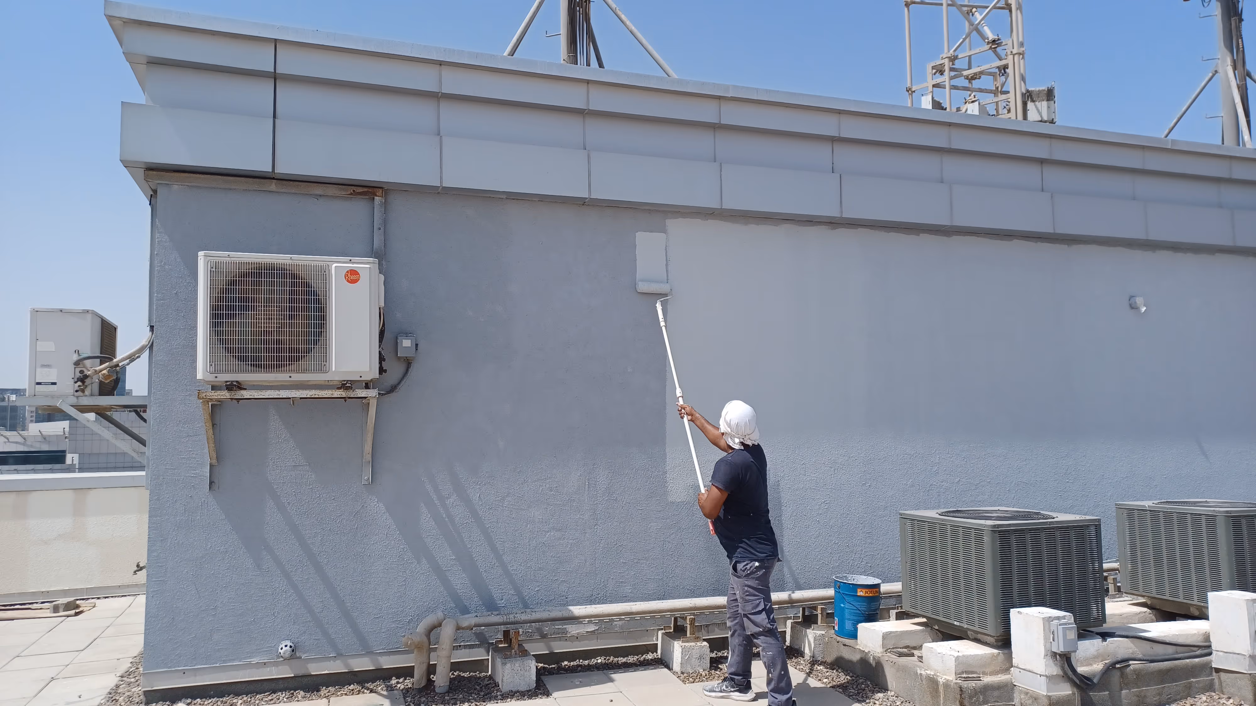 man painting a exterior wall at roof