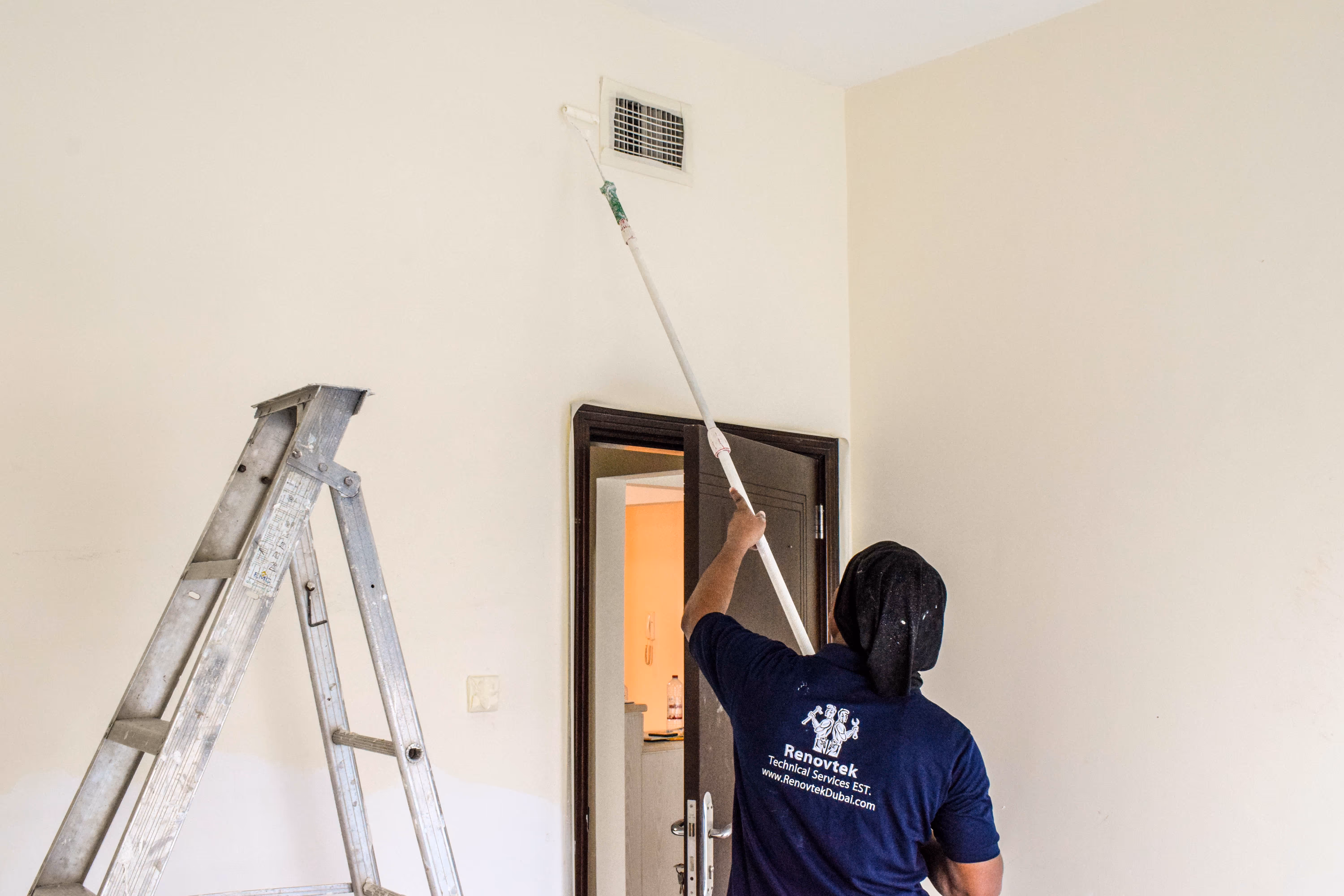A painter is painting a wall using a roller