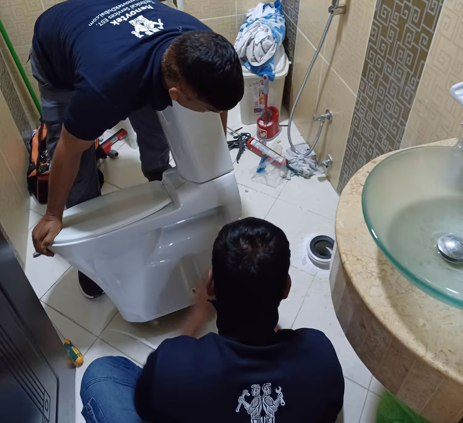 two technisians replacing a toilet in a bathroom