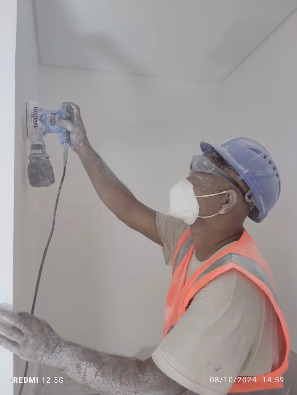 Sanding the wall using electrical sanding machine