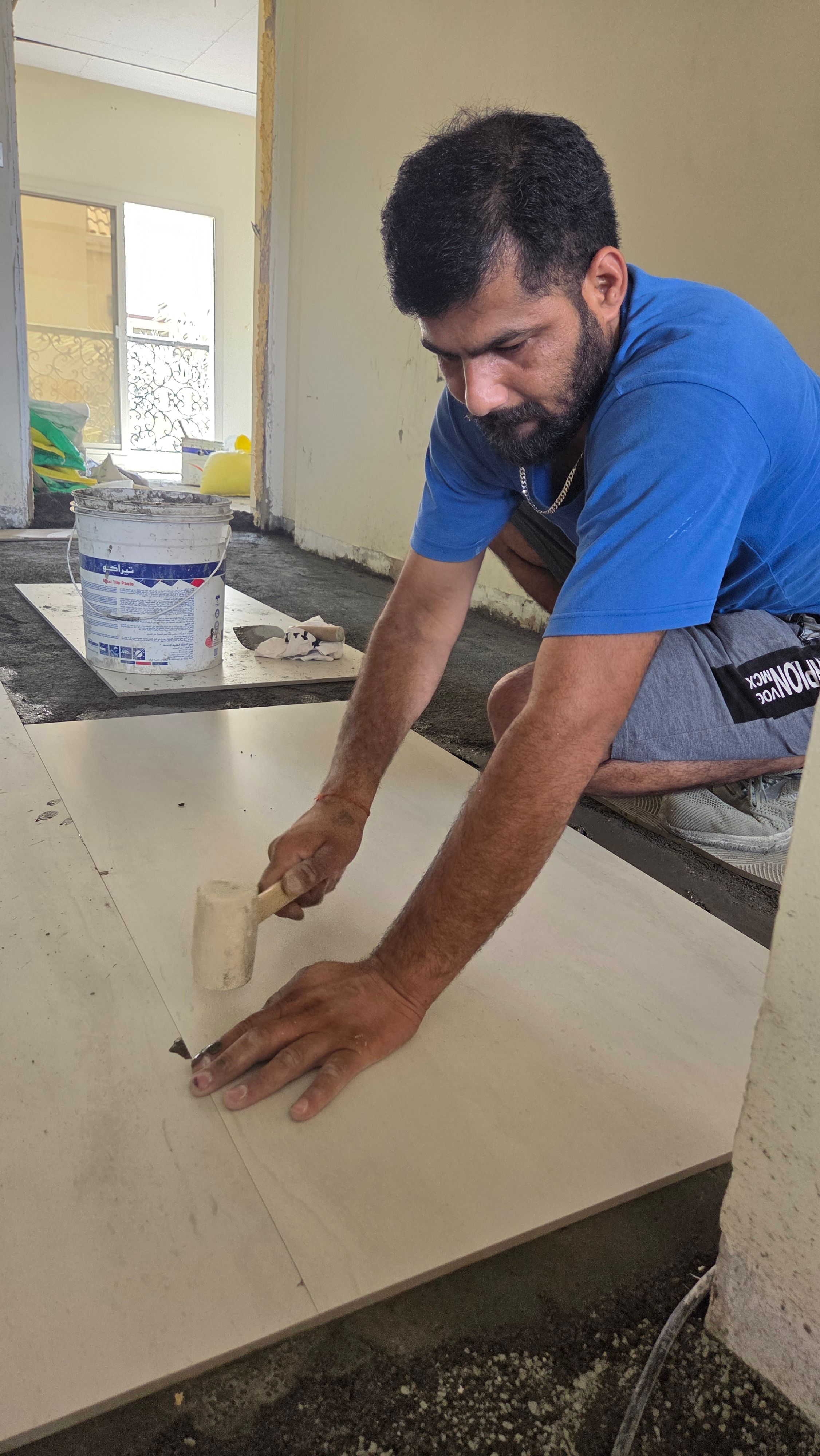Handsome indian man installing floor tile in Dubai